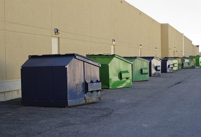 a row of yellow and blue dumpsters at a construction site in Brentwood